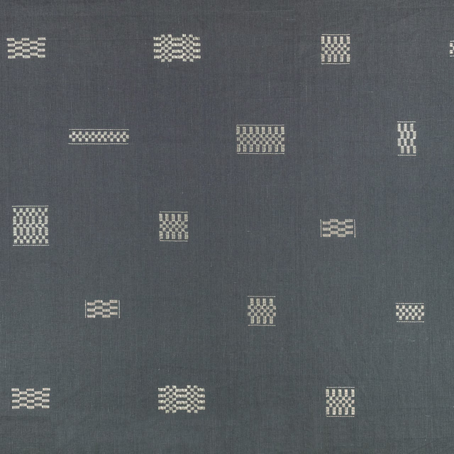 Blue-grey textile with scattered cream geometric embroidered motifs in varied small blocks