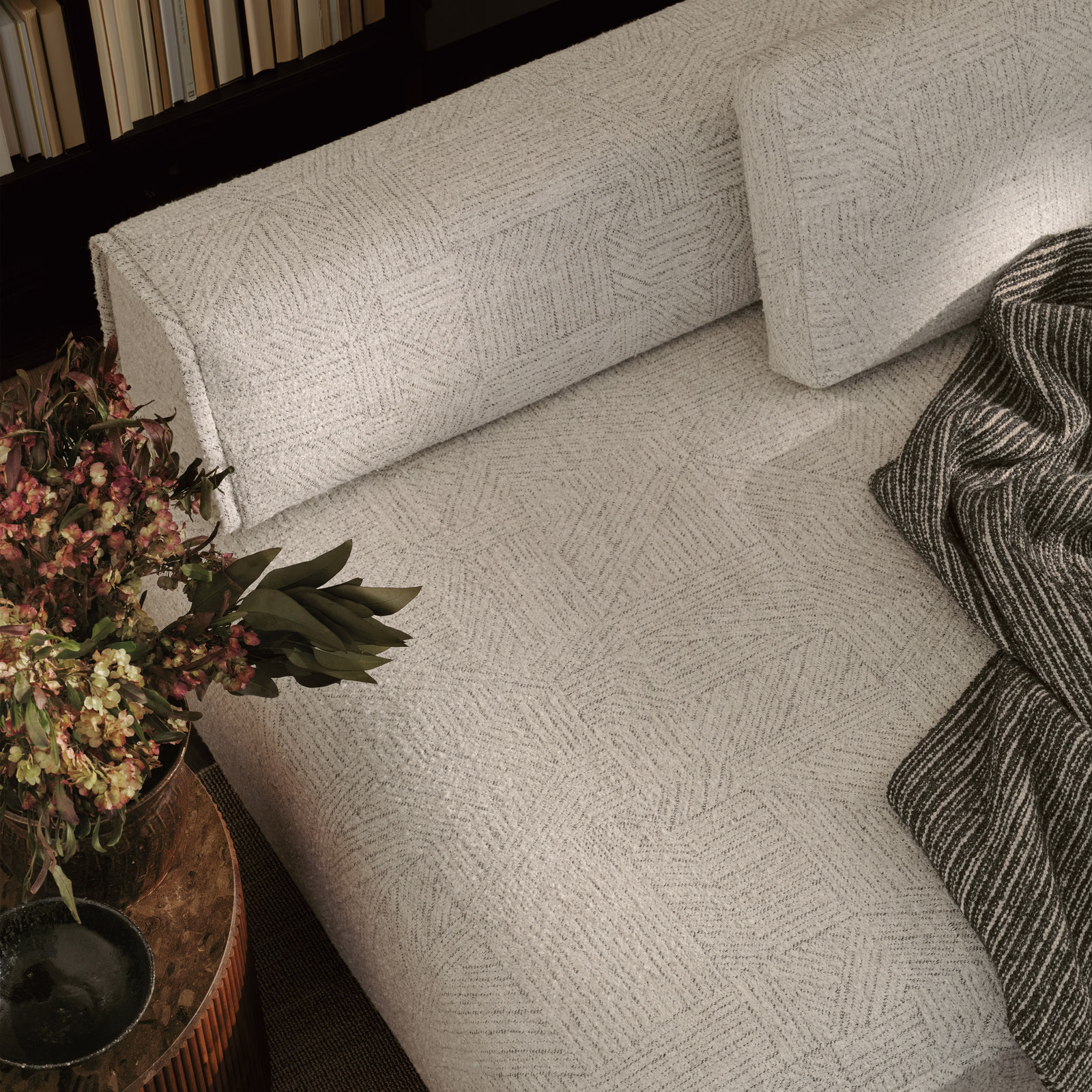 Pale grey geometric woven fabric with fine linear chevrons on a sofa