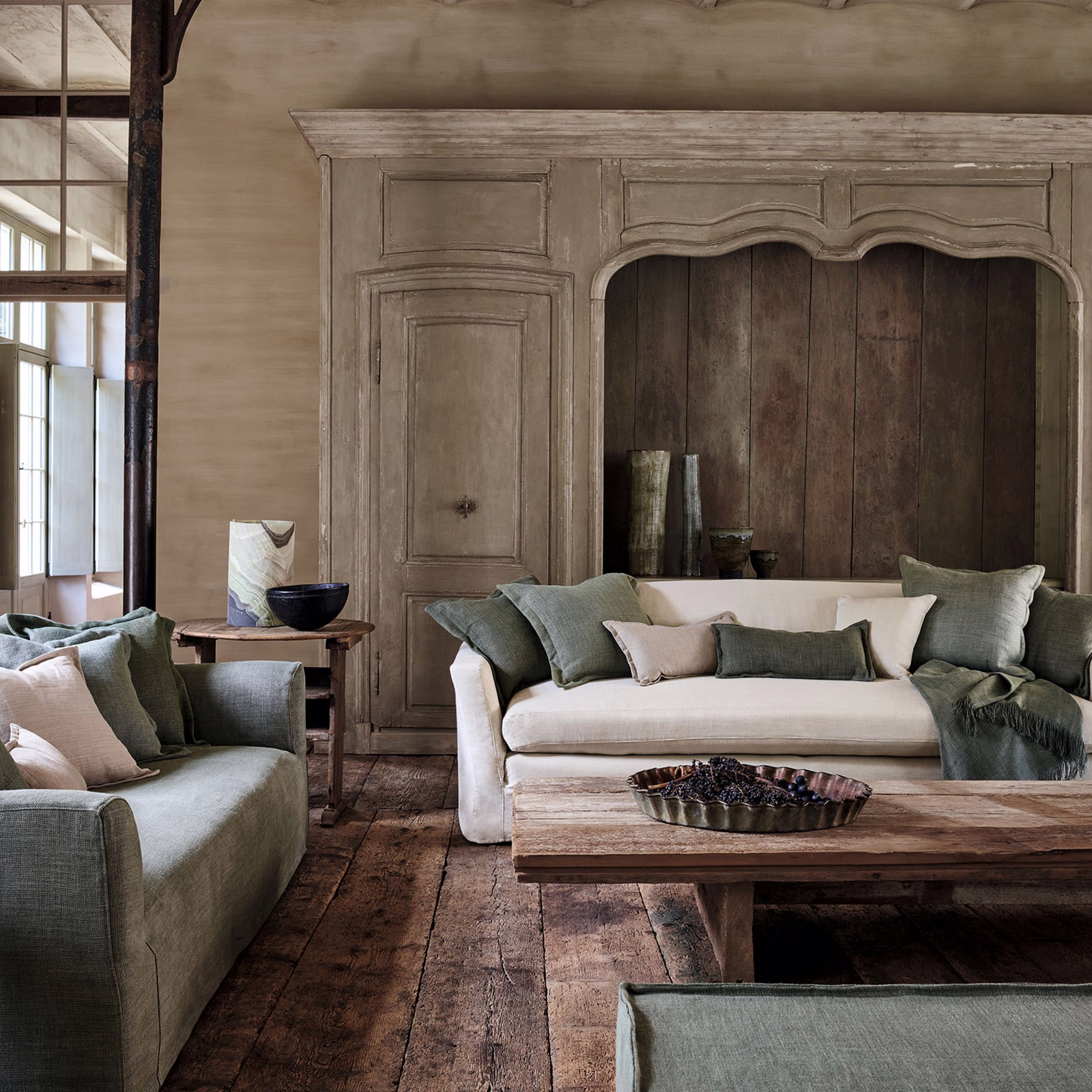 Muted sage-green woven upholstery on sofa cushions and a softly tailored armchair