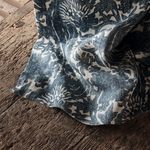 Blue-grey botanical fabric with pale leafy motifs and a visibly textured woven surface
