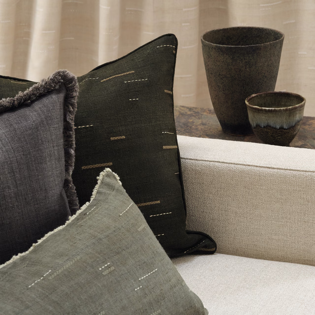 Pebble-grey woven cushion with tiny pale dashes and softly frayed edge