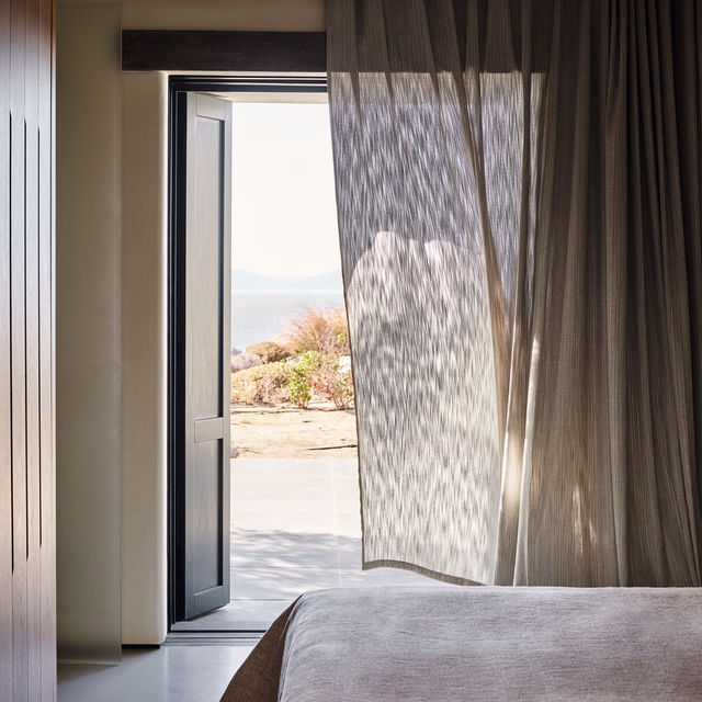 Grey mist sheer with fine vertical ripples filtering daylight beside an open door