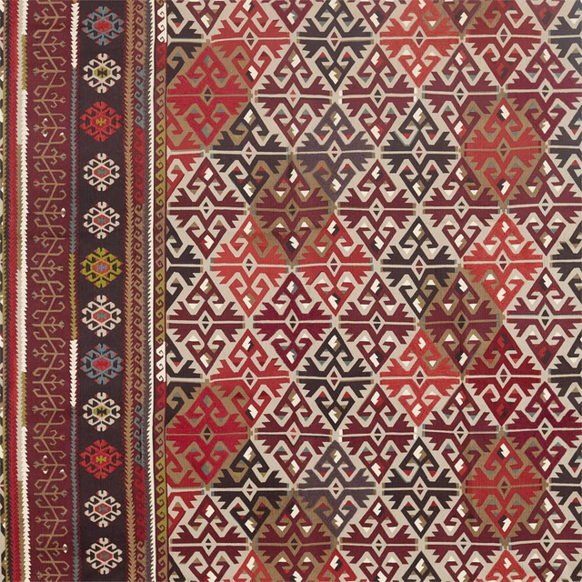 Fig and carmine woven fabric with cream geometric diamonds and a dark patterned border