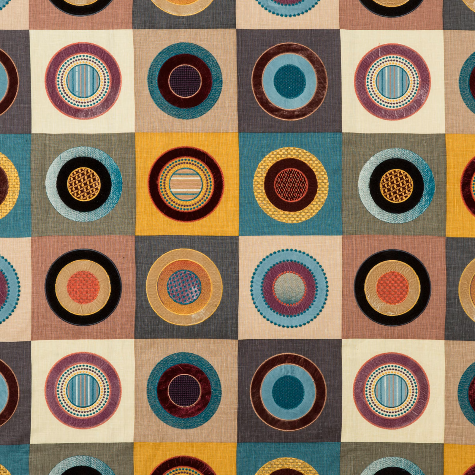 Multicoloured circular medallions in teal, burgundy, ochre and black on a checked woven ground