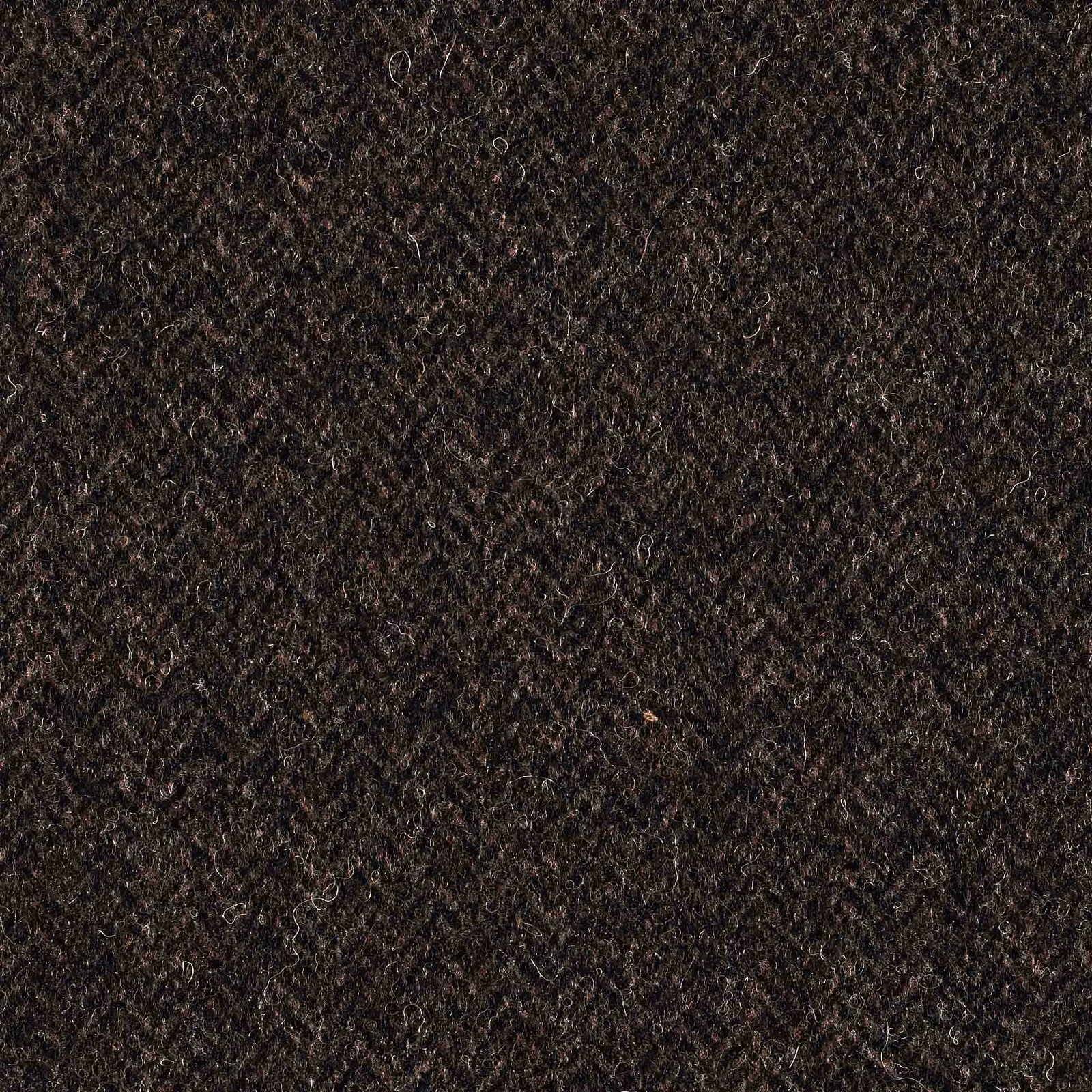Close-up of dense brown-black textile with curled fibres and subtle mottled highlights