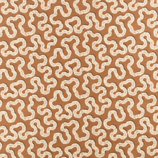 Warm copper textile with ivory looping motifs and softly ribbed woven texture