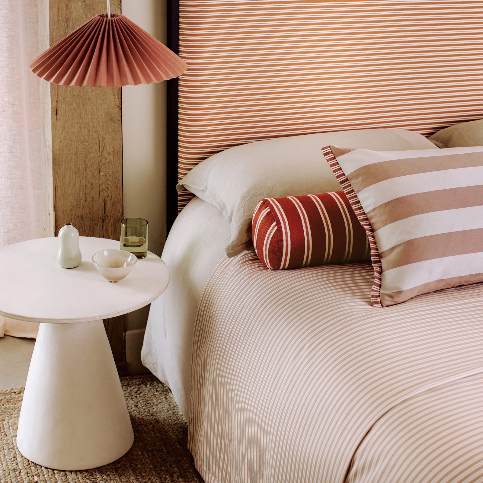 Warm mango and cream fine stripes falling softly across a dressed bed