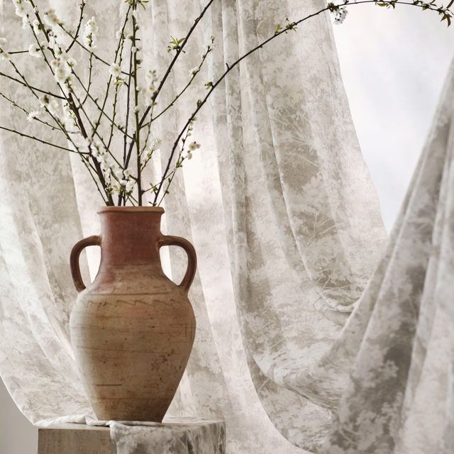 Pale stone taupe sheer fabric with mottled botanical markings in soft window light