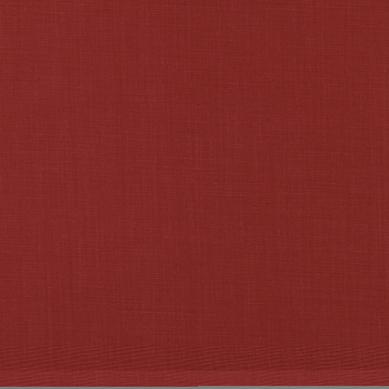 Close-up of plain cranberry-red woven fabric with subtle horizontal slub texture