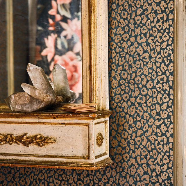 Deep slate-blue wallpaper with dense ochre animal-like spots beside an antique mirror