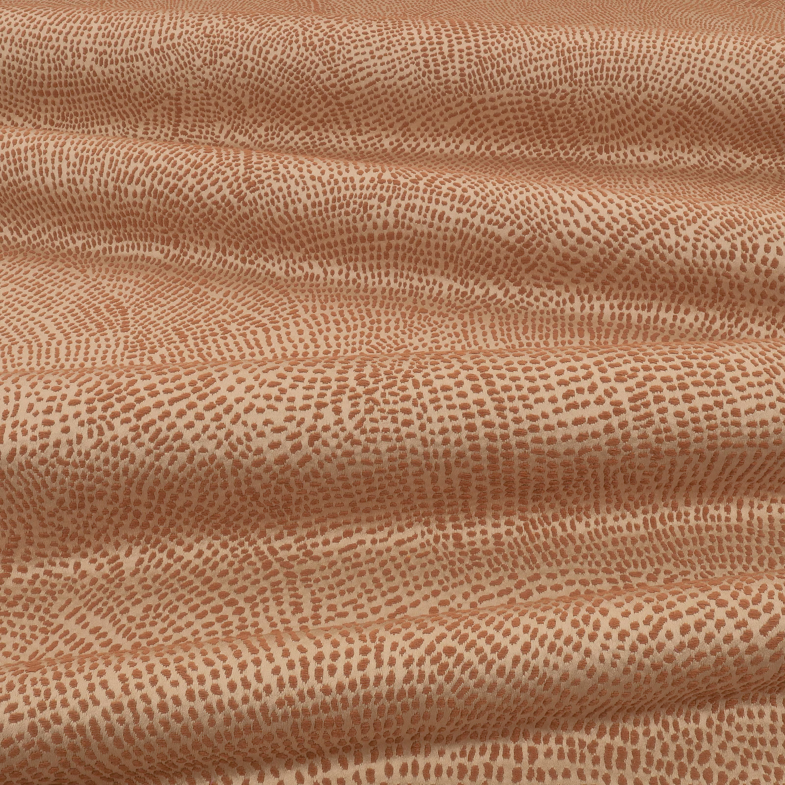 Warm cinnamon fabric with dense pebble-like markings across softly folded cloth