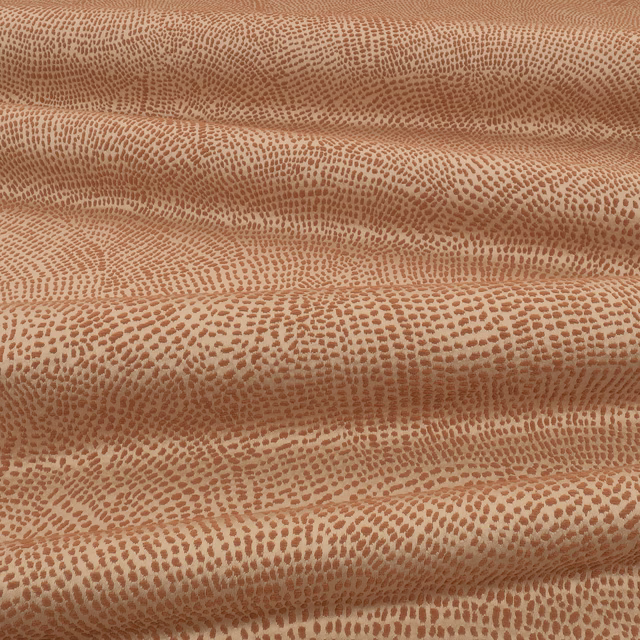 Warm cinnamon fabric with dense pebble-like markings across softly folded cloth