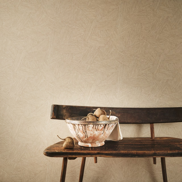 Warm tawny taupe wallpaper with fine overlapping linear marks behind a dark wood bench