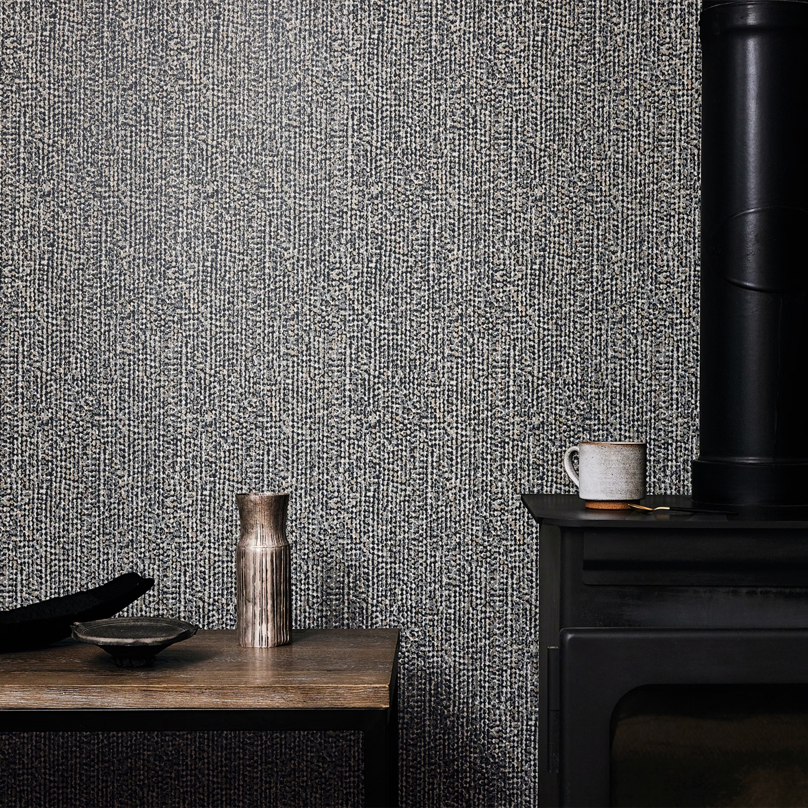 Cool gunmetal wallpaper with dense vertical flecked texture beside black furniture