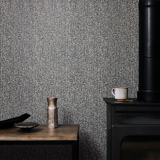 Cool gunmetal wallpaper with dense vertical flecked texture beside black furniture