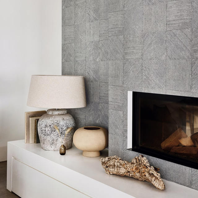 Cool smoke grey textured wallcovering with irregular panels beside a contemporary fireplace