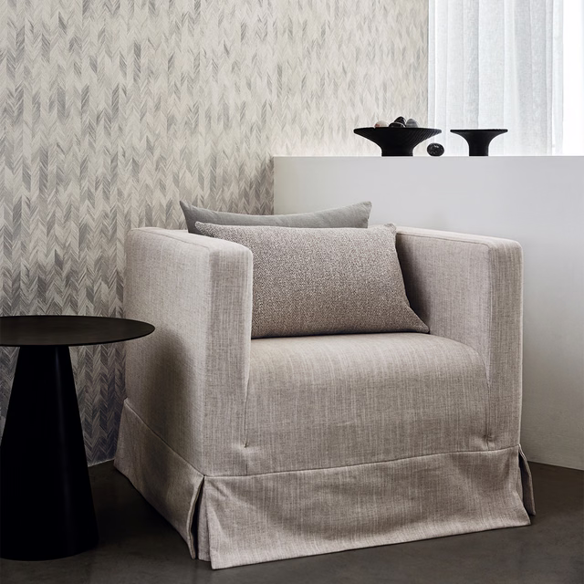 Soft lovat grey-green wallpaper with layered feathered chevrons in a bright room