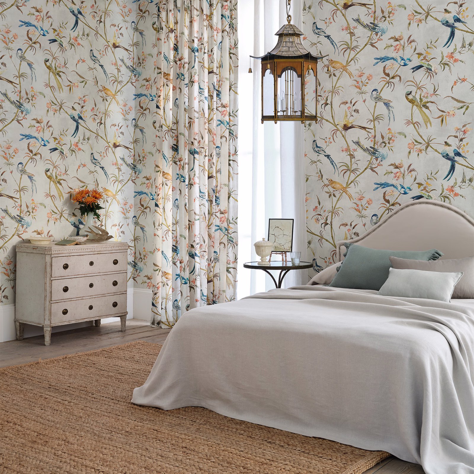 Pale olive-cream botanical wallpaper with blue birds, curling branches and pink blossoms