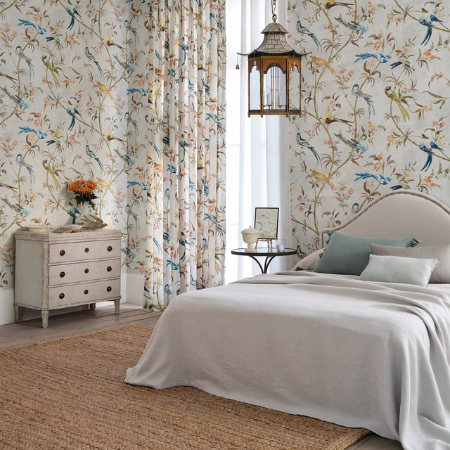 Pale olive-cream botanical wallpaper with blue birds, curling branches and pink blossoms