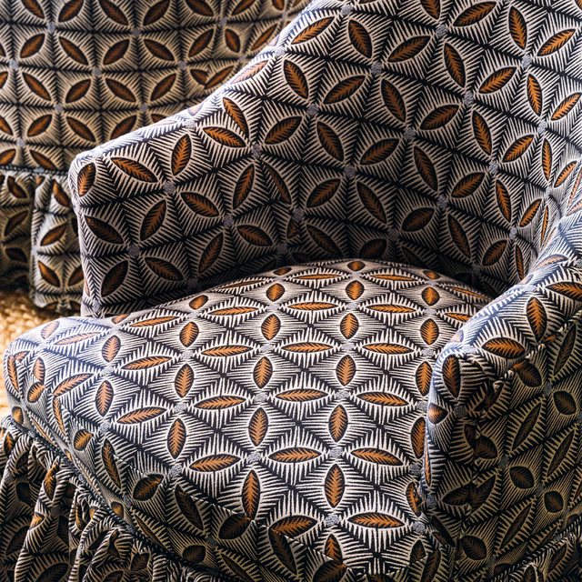 Charcoal and ivory leaf motifs with ochre centres across a textured upholstery fabric