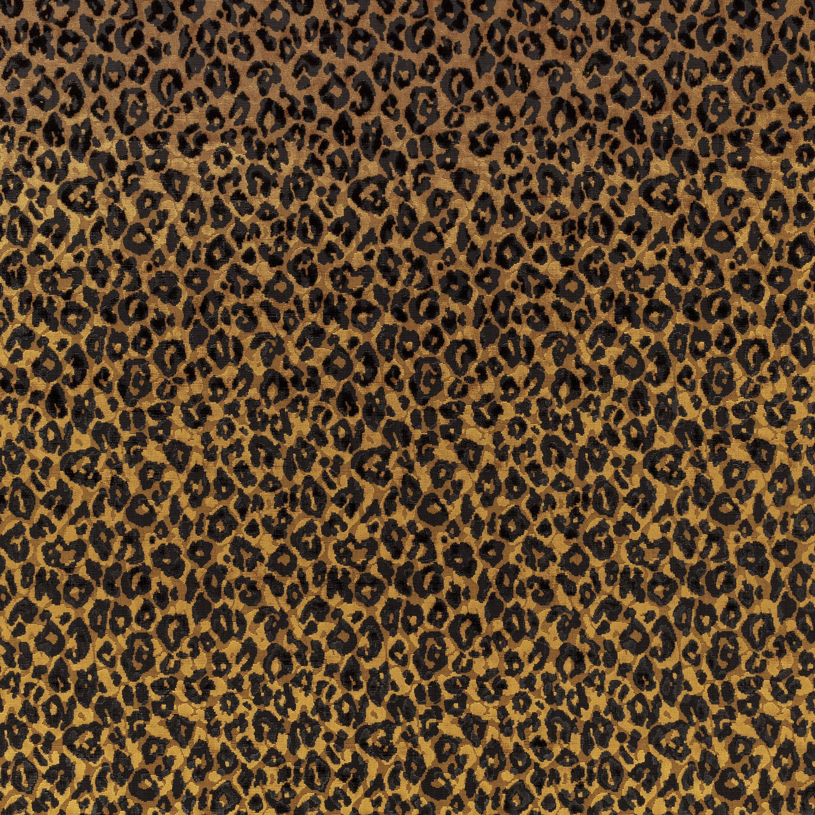 Warm amber-brown textile with dense black leopard spots and a softly textured surface