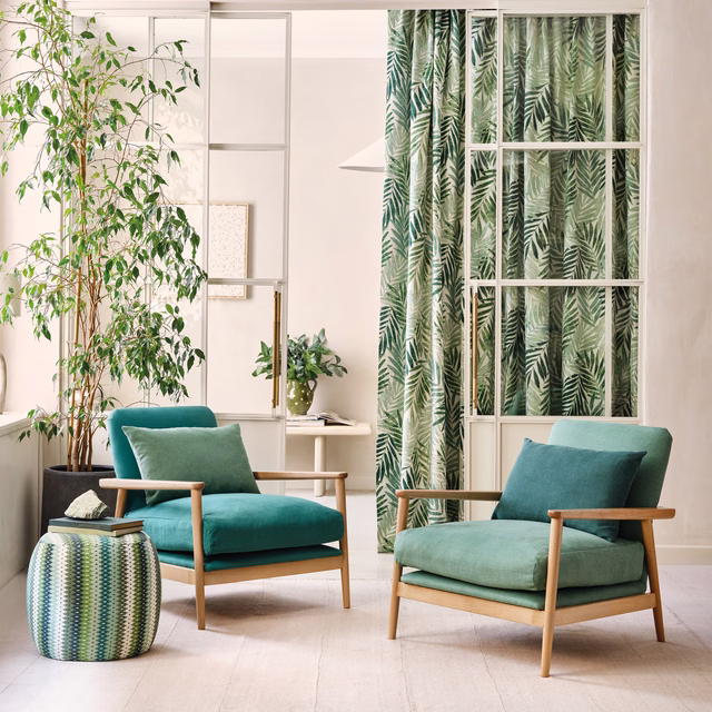 Cream and forest-green leaf fronds repeat across a softly draped curtain