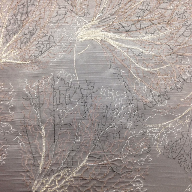 Grey botanical fabric swatch with shimmering leaf outlines and textured weave
