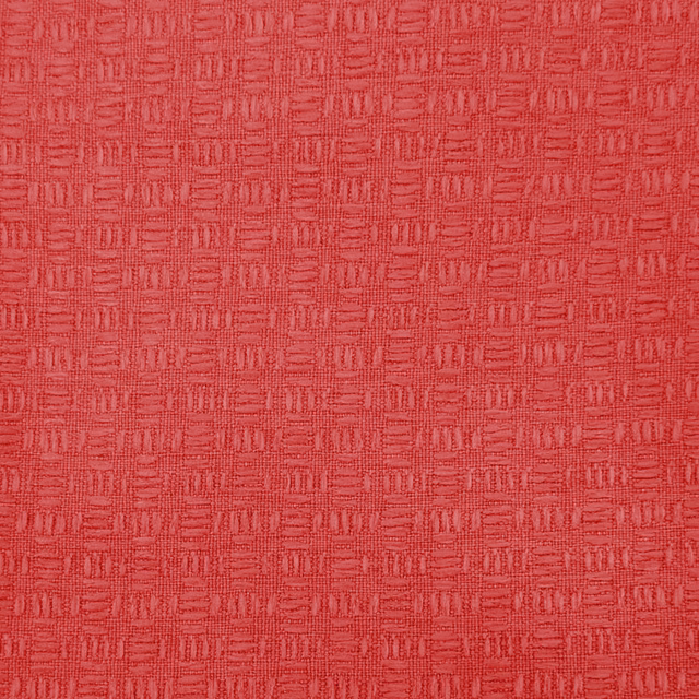 Close-up of bright coral-red woven fabric with small geometric texture