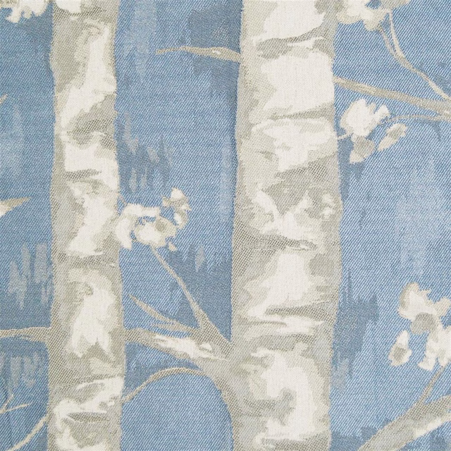 Blue woven floral fabric with pale tree trunks and blossoms