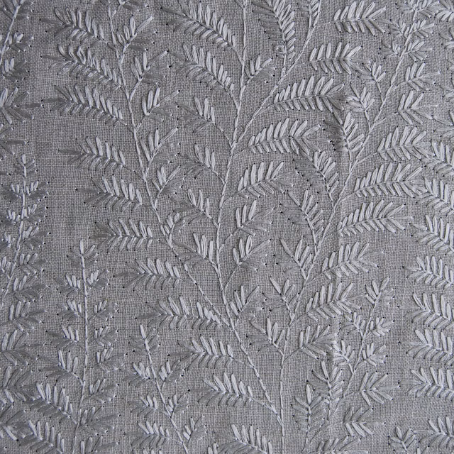 Close-up of grey botanical fern embroidery on a linen-look fabric ground