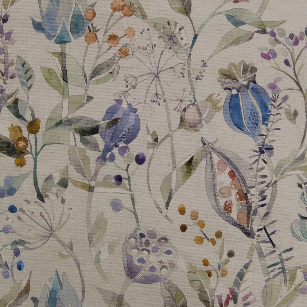 Painterly botanical fabric with soft blue flowers, lilac accents and leafy stems on a pale ground