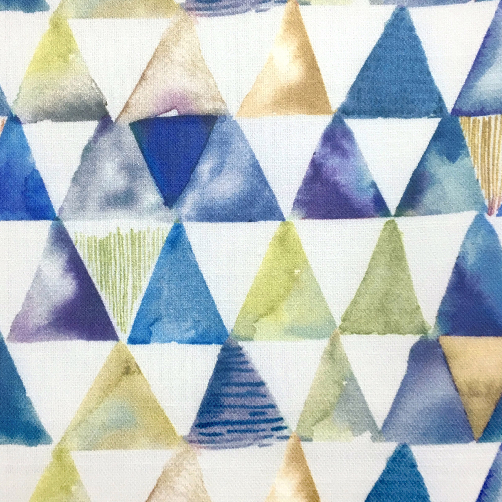 Geometric triangle print in warm orange, blue, lilac and green on white fabric
