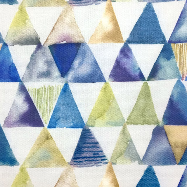 Geometric triangle print in warm orange, blue, lilac and green on white fabric
