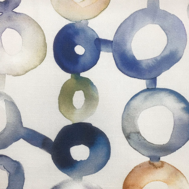 Painterly blue and green ring motifs on a white woven fabric ground