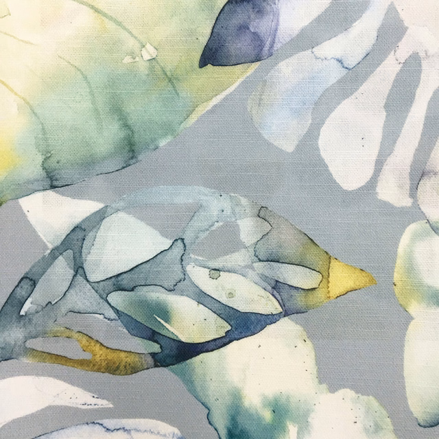 Painterly botanical fabric on a soft blue-grey ground with pale leaves and green accents