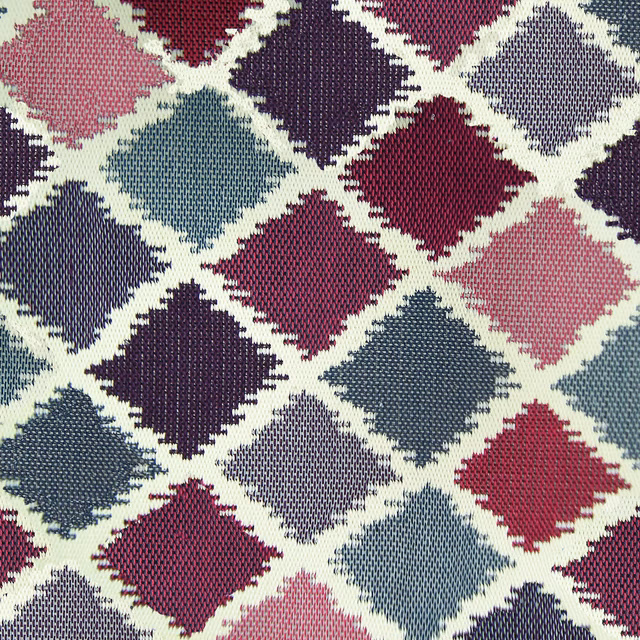Close-up of geometric diamond woven fabric in plum, teal, pink and cream
