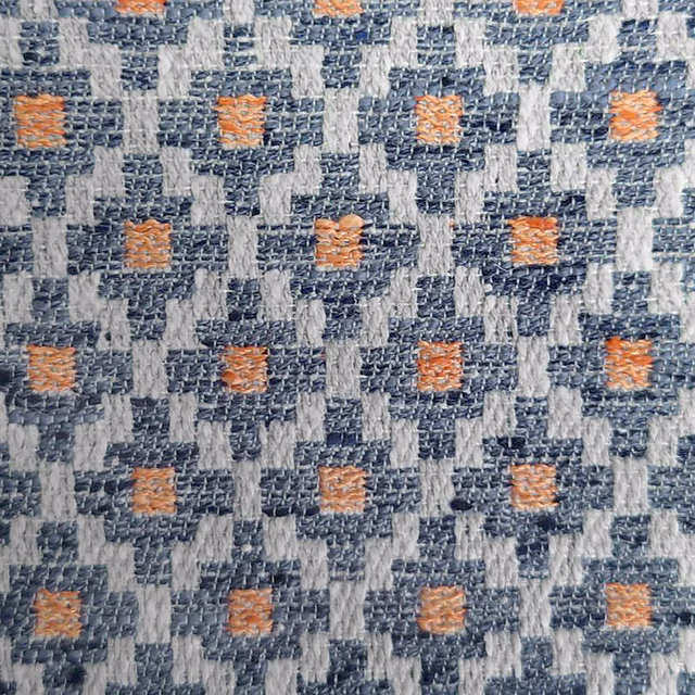 Close-up of a blue and grey geometric woven fabric with orange accents