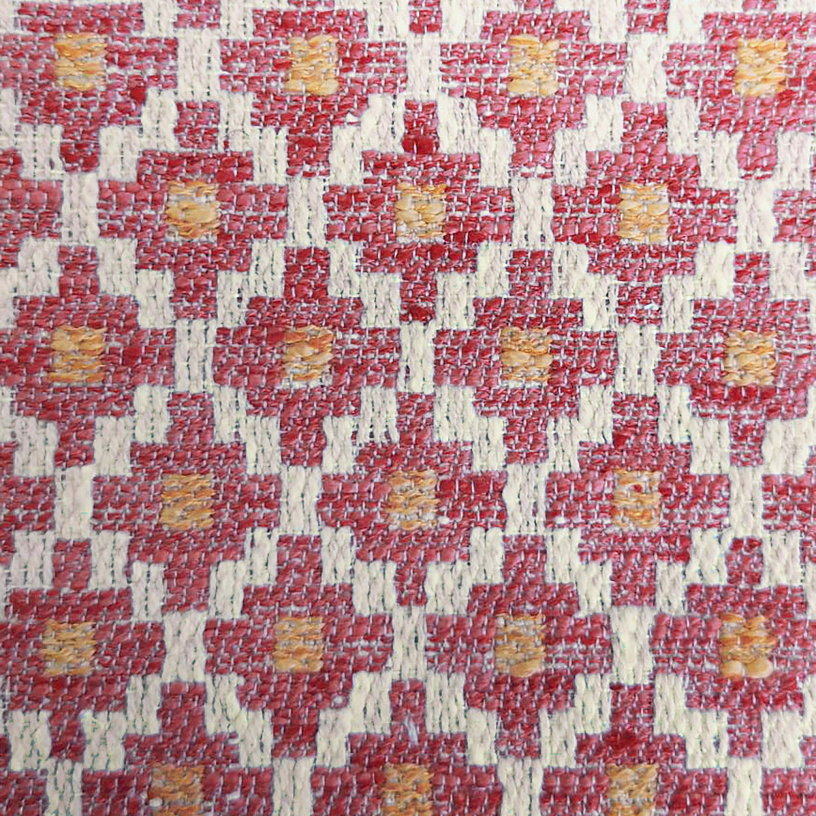 Close-up of coral-orange geometric woven fabric with cream lattice and ochre flecks