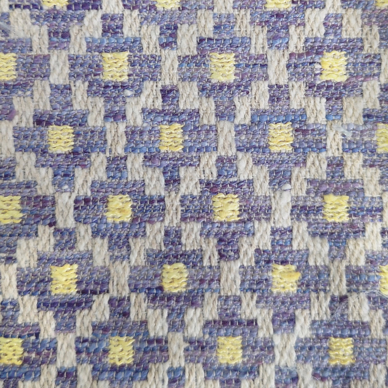 Close-up of a purple, blue and cream geometric woven fabric with yellow accents