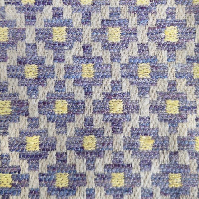 Close-up of a purple, blue and cream geometric woven fabric with yellow accents