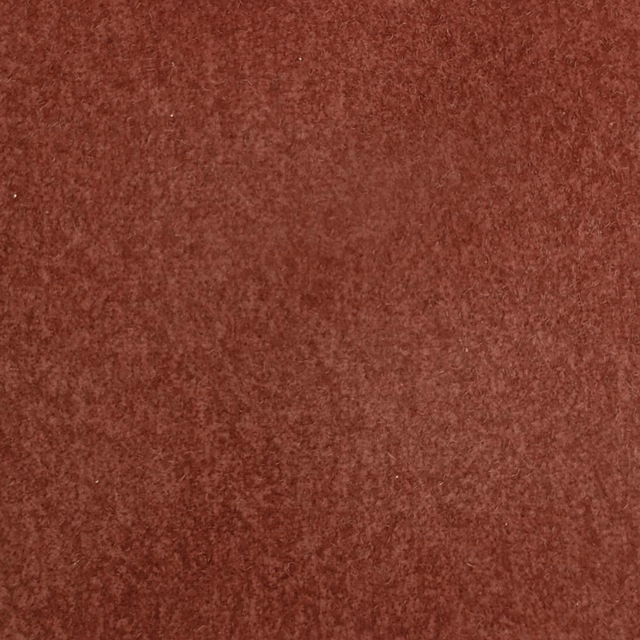 Close-up of a deep brick-red textured plain fabric with a mottled finish