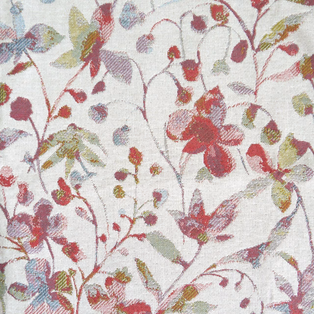 Close-up of woven floral fabric with raspberry red blooms and sage leaves on a pale ground