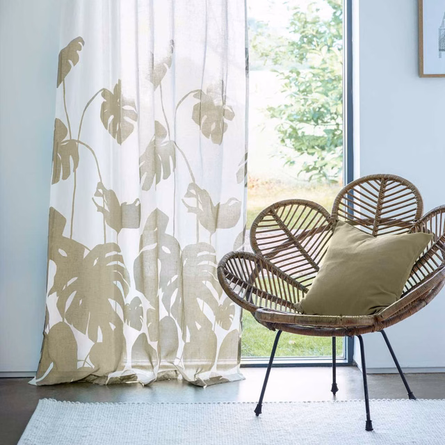 Ivory sheer curtain with taupe-olive split-leaf botanical silhouettes in sunlight