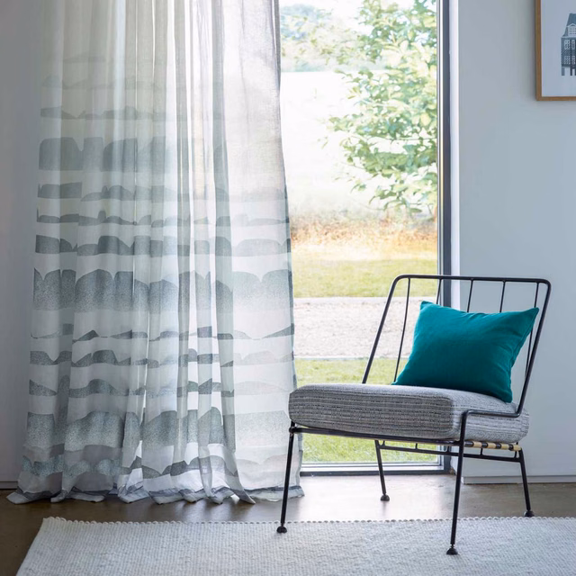 Cool slate-grey sheer with translucent horizontal wave bands at a bright window
