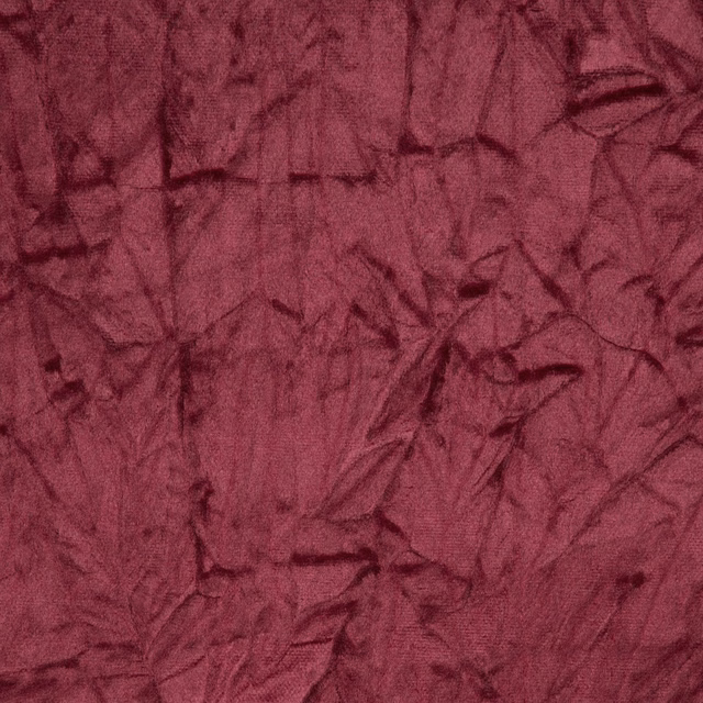 Deep mulberry-red fabric with dark crumpled abstract markings and tactile woven texture