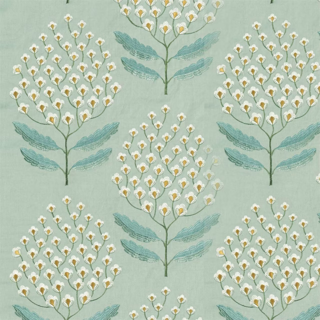 Soft blue-green fabric with repeated botanical tree motifs, white and gold blossoms, and teal leaves
