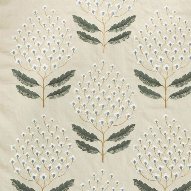 Cream botanical fabric with fern-like green motifs and tiny blue flower heads