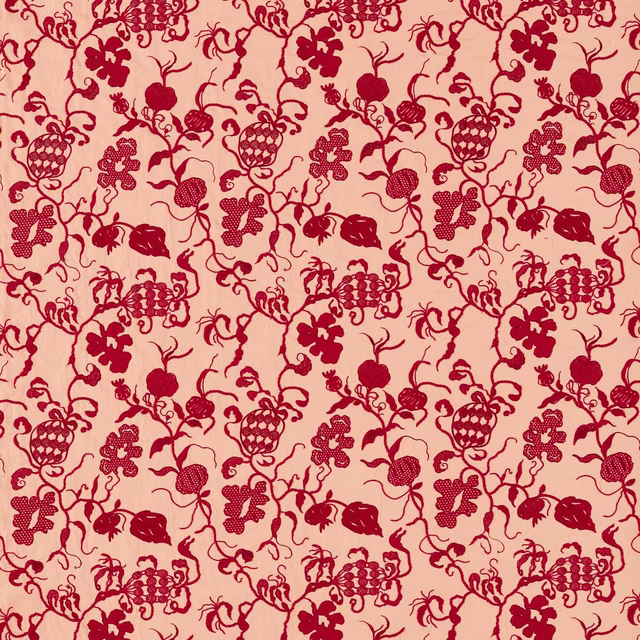 Close-up of red botanical print on a soft conch-pink fabric ground