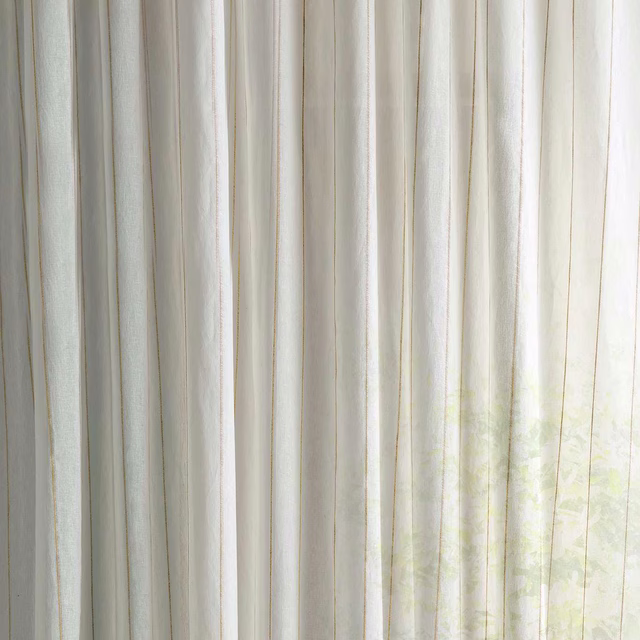 Sheer cream fabric with faint pale mimosa tint and vertical folds