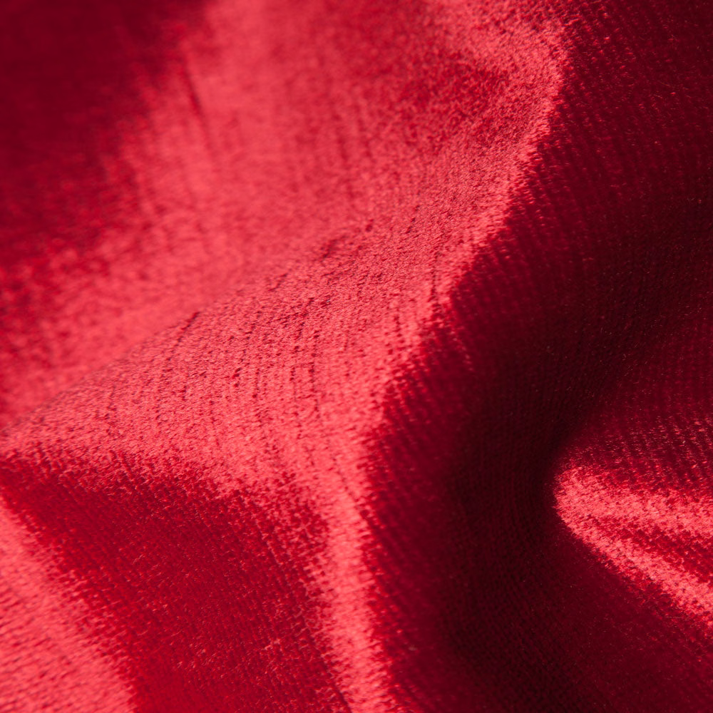 Close-up of deep crimson plain fabric with velvety pile and dark folded shadows